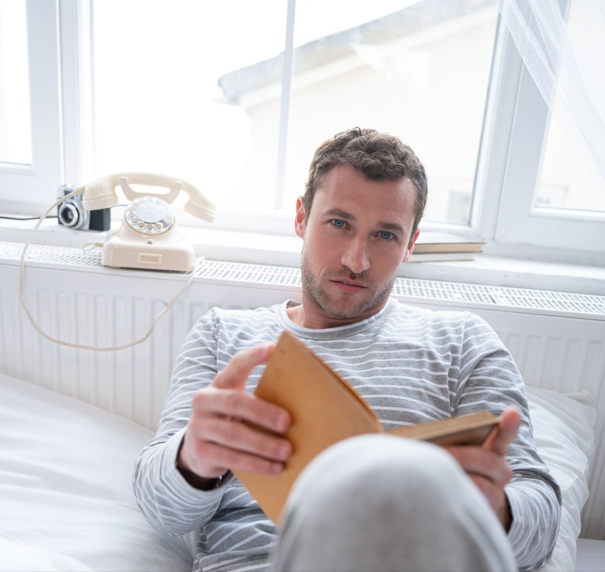 Mann auf Couch in Pyjama beim Lesen